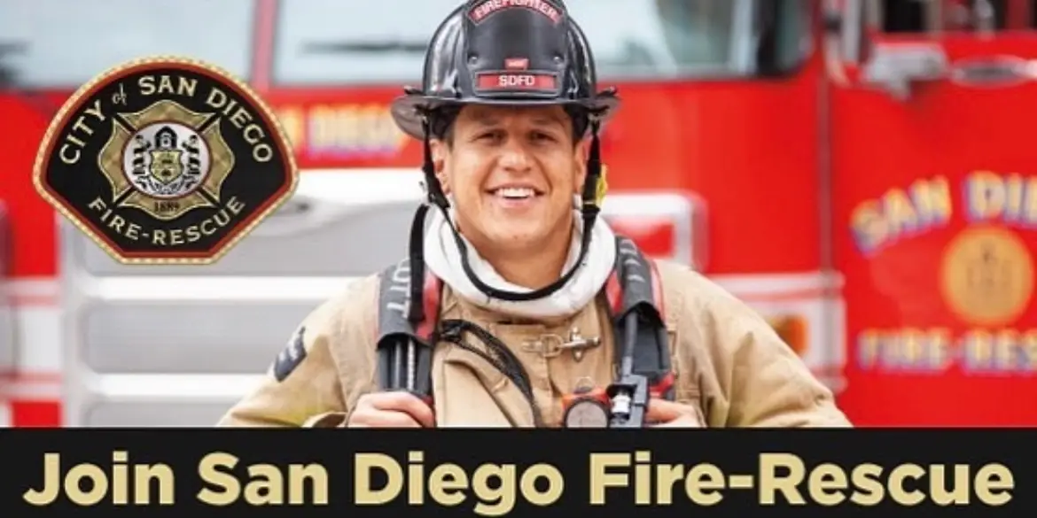 Image of a firefighter wearing a helmet and uniform standing in front of a red fire engine